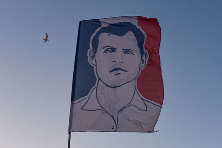 A flag displaying the face of Quentin Deranque is carried during the march against political violence from Largo di Torre Argentina to Piazza del Campidoglio.