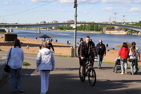 Tourists, residents and visitors of the city on a walk along the embankment of the Volkhov River and the Kremlin.