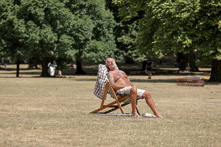 A man sunbathes at St James's Park on a very hot and sunny day.