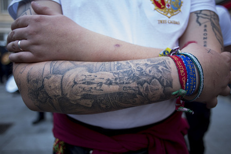 A member of the brotherhood has a tattoo of a crucified Christ on his arm during the procession of the Holy Christ of the Three Falls from the Royal Parish Church of Santiago and San Juan Bautista, which wound through the streets of Madrid on Holy Wednesday.