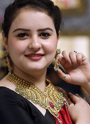 A woman looks on after wearing gold jewelry at the showroom on the occasion of Akshaya Tritiya at PP Jewellers in New Delhi. People invest and purchase valuable assets, like gold on the auspicious day of Akshay Tritiya.