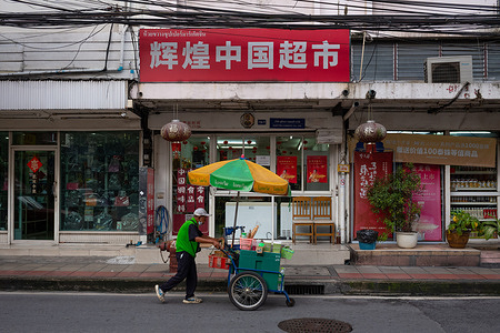 A vendor with his trolley passes by a Chinese supermarket.