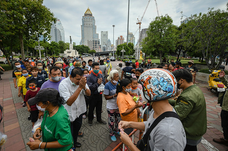 BANGKOK, THAILAND - APRIL 18, 2020:
Homeless people queue to receive help of one hundred baht (around $3USD) per person at Lumpini Park.
Many homeless people, who often have low wage jobs and cannot afford a place of their own gather at Lumphini Park to receive help and donations after they were left stranded as government urged businesses to close to contain the spread of covid 19 pandemic.