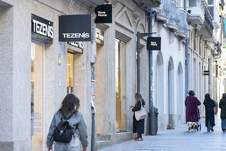 Pedestrians walk past the Italian clothing label specializing in bras, lingerie, and pajamas owned by Calzedonia group, Tezenis, and Spanish furniture and home-decor brand, Kave Home, stores in Spain.