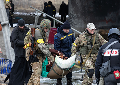 Servicemen carry a person that can't move during the evacuation.Thousands of residents of Irpin have to abandon their homes and evacuate as Russian troops are bombing a peaceful city. War refugees in Ukraine.