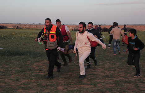 Medical workers seen carrying an injured person during Clashes between Palestinians and Israeli forces after a large-scale march on the separation fence between Gaza and Israel east of Khan Younis.