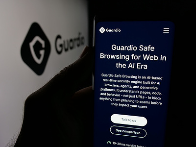 In this photo illustration, a person is holding a cellphone with the webpage of Israeli company Guardio Ltd. (Guard.io) on screen in front of logo.