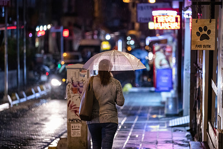 During rain in Kadikoy, a woman shelters beneath an umbrella while walking along Bahariye Street.
