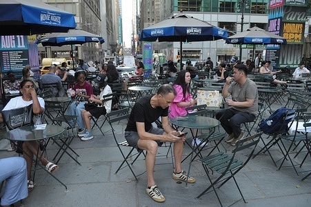 People sit at tables in Bryant Park, Manhattan.