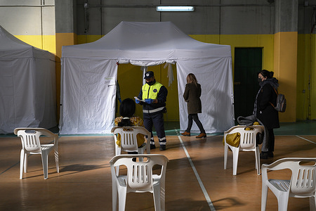 A member of the Civil Protection (C) seen with documents in the hall during the vaccination program.
The Covid 19 vaccination campaign continued during Christmas with an open day in the Municipal Gym. As Omicron surges, the Azienda Sanitaria Provinciale (ASP, Provincial Health Company) of Vibo Valentia is planning to maintain its vaccination campaign throughout the Christmas and New Year holidays. The local Civil Protection (Protezione Civile)is providing support for the campaign.