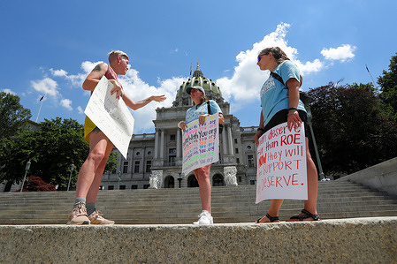Abortion rights advocate Cate Tershak (left) speaks with anti-abortion demonstrators Elizabeth McNulty (center) and Mary Krolicki (right), both from Students for Life of America, as they hold a rally on the steps of the Pennsylvania State Capitol. The rally was held in response to the United States Supreme Court ruling in Dobbs v Jackson Women's Health Organization which overturned the constitutional right to abortion.