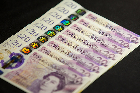 In this photo illustration banknotes of the pound sterling, The Bank of England £20 notes with the image of Queen Elizabeth II are seen displayed.