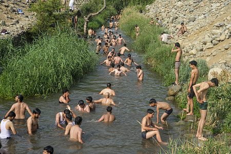 People cool off in a stream during a hot summer day in the outskirts of Srinagar. Severe heat waves sweeps across Kashmir valley, pushing temperatures to unprecedented highs in several locations. Local weather office has advised residents to avoid outdoor activities during peak hours, stay hydrated, and take necessary precautions to cope with the ongoing heatwave.