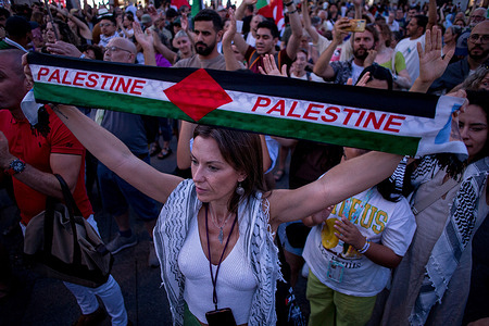 A protester raises a scarf reading "Palestine" during a pro-Palestinian demonstration in Madrid’s Plaza del Sol, denouncing Israeli attacks on Gaza.