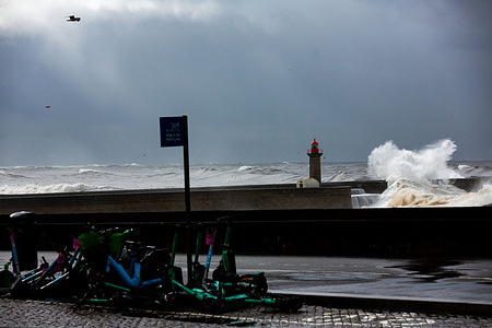 Electric scooters lie scattered across a rain-soaked promenade as waves crash violently against Porto’s pier during Storm Ingrid. The city’s shared mobility station stands in stark contrast to the turbulent Atlantic backdrop, where the iconic lighthouse braces against nature’s fury. Porto, Portugal, January 24, 2026. Storm Ingrid slams Porto’s iconic lighthouse with powerful waves, forcing authorities to restrict access along the Atlantic promenade. Barricades and warning tape line the seafront as severe weather disrupts coastal activity and highlights the intensity of the storm.