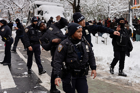 NYPD officers dodge snowballs as they move people out of the street during Sidetalk's snowball fight in Washington Square Park.