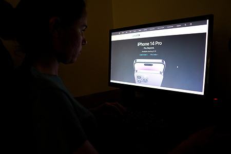 In this photo illustration, a woman is seen accessing Apple website to see the new iPhone 14 PRO. The device was recently announced. It has a brighter screen, longer battery life, and new image processing algorithms that allow for better low-light photography and more faithful color reproduction.
