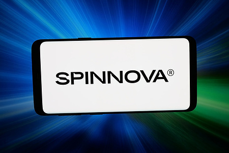 In this photo illustration, the logo of Finnish textile material company Spinnova Oyj is displayed on a smartphone in front of abstract background on computer screen.
