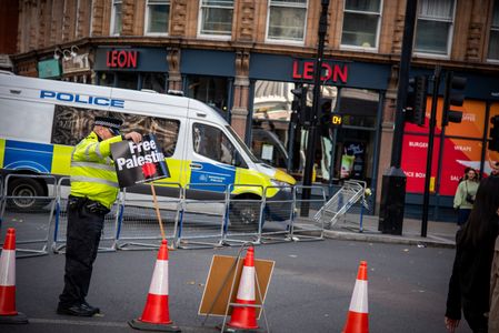 A police officer repositions a placard during the National March for Palestine: End the Genocide Protest. The National March for Palestine: End the Genocide took place in central London. Marking three years since the escalation of conflict in October 2023, thousands of demonstrators gathered to protest UK complicity, demand an immediate arms embargo, and call for comprehensive sanctions against Israel.