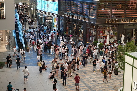 A large crowd fills the open plaza of Sanlitun’s shopping complex, with escalators and Polo Ralph Lauren visible among the bustling activity.