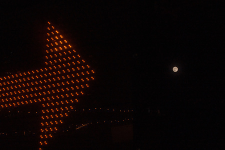 An orange traffic indicator points towards the rising full Cold supermoon as seen from Liberty State Park.