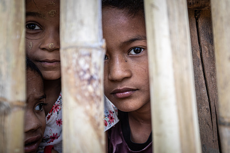 Children seen behind a bamboo fence in Mae La Temporary Shelter camp. Mae La or Maela is a refugee camp in Thailand near the border with Myanmar (Burma), that was established in 1984 in the Tha Song Yang District, Tak Province (550km from capital Bangkok) in the Dawna Range area where around 50,000 Karen refugees live after fleeing armed conflict and persecution by the Burmese army also known as "Tatmadaw". Mae La has been established as a 'Temporary Shelter' for over 38 years now, with almost no sign of hope for the people stuck inside to be able to go back into their country, especially with the ongoing conflict in Myanmar following the February 2021 coup by General Min Aung Hlaing.