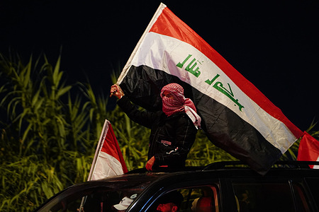 Iraqi young man waves flag as people celebrate following Iraq’s qualification to the 2026 World Cup international playoff. Iraq defeated the UAE 2-1 at Basra International Stadium in the second leg of the final round of the Asian qualifiers for the World Cup.