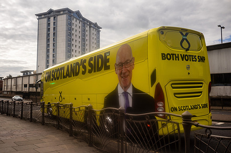 First Minister of Scotland John Swinney’s SNP “Battle Bus” draws up to the Hamilton office of candidate Alex Kerr. On the morning of 6th of May, the day before the Scottish parliamentary elections, First Minister of Scotland John Swinney visits Hamilton in South Lanarkshire, the constituency of SNP candidate Alex Kerr to kick off the final day of campaigning by meeting potential voters and owners of local businesses.