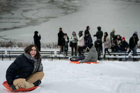 A woman smiles as she sleds down Cherry Hill in Central Park after an overnight snowstorm on December 27, 2025, in New York City.