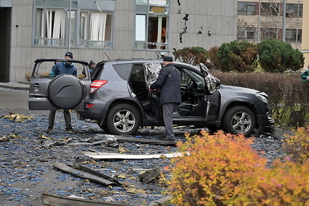 A man inspects a damaged car in a yard of an apartment building damaged by a Russian strike.