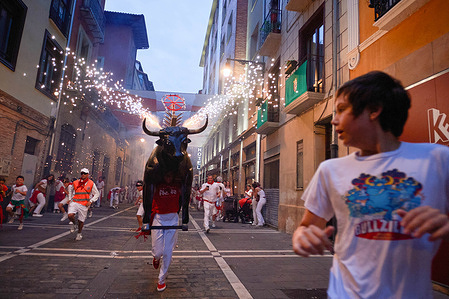 Several children run as the fire bull chases them during the San FermÌn 2024 festivities. At ten at night during the San Fermín festivities, it is one of the events scheduled for adults and children, it is the "torico" fire bull, it is a cardboard frame pretending to be a bull with horns, on its back it carries rockets and the mission is to chase children and adults during the San Fermín 2024 festivities.