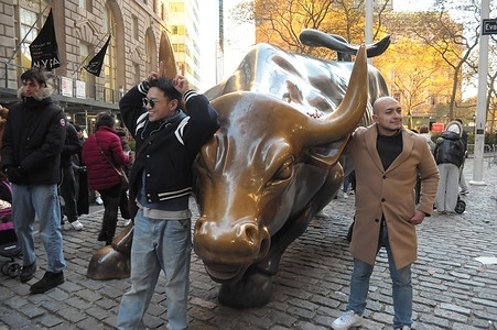People take photos by the "Charging Bull" statue in the Financial District in Manhattan, New York City.