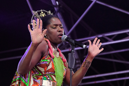 British-Nigerian singer and lyricist and lead vocalist Eno Williams with British Afrofunk band Ibibio Sound System performing live on stage at Boomtown fair festival. Boomtown is a British music festival held every year on the Matterley Estate in South Downs National Park, near Winchester. Ibibio Sound Machine is an English electronic afro-funk band from London. Formed in 2013, the band currently consists of vocalist Eno Williams, guitarist Alfred Kari Bannerman, percussionist Afla Sackey, drummer Joseph Amoako, bassist Philip PK Ambrose, trombonist/keyboardist Tony Hayden, trumpeter/keyboardist Scott Baylis and saxophonist/keyboardist Max Grunhard.