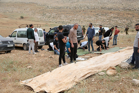 Israeli soldiers surround Palestinian worshippers as they perform prayers on their land, which had been confiscated by the Israeli army and Jewish settlers. Palestinian families have been displaced from their farms after being harassed by a group of Jewish settlers who stole their sheep and subjected them to other forms of harassment in the West Bank.