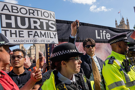 A pro-life anti-abortion Catholic holds aloft rosary beads behind a cordon of Police. Pro-life demonstrators marched through Westminster for “March for Life”, heading towards Parliament Square where they were met by hundreds of pro-choice campaigners from the “Stand Up for Choice” counter-protest. The two opposing groups clashed both physically and verbally in their opposing views on abortion rights.
