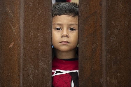 A young Asylum seeker peers through the border wall. As Title 42 has officially expired in the United States, which was policy established during the Trump-era allowing authorities including Border Patrol to turn away migrants at the borders to prevent the ongoing Corona Virus pandemic, Asylum seekers can be seen camped between the San Diego, California border and Mexico border waiting to be processed in to United States system. Scattered with an array of nationalities, these migrants have traveled from near and far with the things that they could on their long journeys. Some have been waiting for days and many others for weeks, waiting for the caravans that Border Patrol are using to file individuals one by one to be officially processed with a court date and necessities to survive, as they await for their unknown fate.