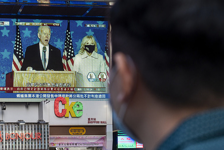 A pedestrian watches the Democrat candidate Joe Biden speaking on a large screen broadcasting the live news report about the US Presidential election.
