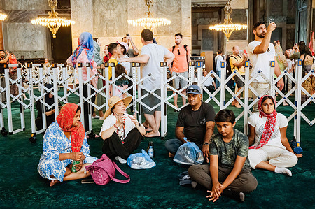 A group of tourists seen sitting on the floor. During the first day of the Muslim Feast of Sacrifice (Eid al-Adha or Kurban Bayrami in Turkish), foreign and local tourists visit the ancient Byzantine church of Hagia Sofia (Ayasofya in Turkish, Saint Sophia, in English), re-converted in the Great Mosque of Ayasofya in 2020, after being turned into a public museum in 1935.