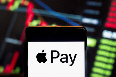 In this photo illustration, the mobile payment and digital wallet service by Apple, Apple Pay, logo seen displayed on a smartphone with an economic stock exchange index graph in the background.