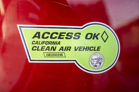 A California Clean Air Vehicle (CAV) decal sticker seen on a car seen. Starting October 1 2025, federal policy changes will invalidate these decals, ending single-occupant access to carpool (HOV) lanes and reduced tolls. Drivers who continue using decals risk citations.