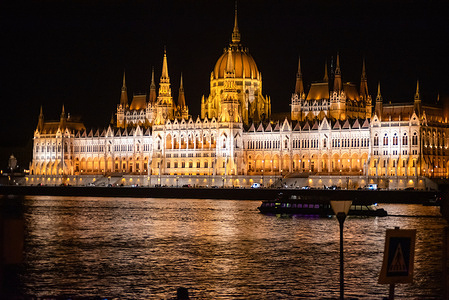 A boat sails on the River Danube at night front of the Hungarian Parliament building in Budapest. Budapest, Hungary’s capital, is bisected by the River Danube. It is beautiful city especially at night. Golden-illuminated historical landmarks were built along the Danube.