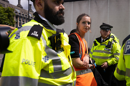 A protester from Just Stop Oil is being arrested by police officers outside Parliament Square during the demonstration. The climate group staged their biggest protest yet with a series of Back-To-Back Slow Marches to Parliament Square, demanding that the government stops issuing new fossil fuel licences.