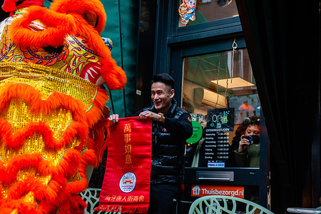 A man is receiving the blessing from the lions. The Chinese-Asian district in The Hague celebrated the Chinese New Year, the year of the Horse, with lion and dragon dancers, parading through the district. The celebration was meant to chase away evil spirits and bring prosperity and happiness for the new year. The dragon symbolizes power and nobility, while the lion brings good luck and prosperity. The Chinese New Year is based on the Chinese zodiac.