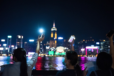 Protesters shine their phone lights while facing the harbour during the demonstration.
Protesters held hands to create long human chains in peaceful protest against the extradition bill. Some protesters carried various placards asking and thanking other countries for their support while others also shined their phone lights as a sign of unity and peace.