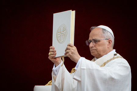 Pope Leo XIV raises the Gospel at the end of readings during the Holy Mass on Corpus Christi Day in St. John Lateran Archbasilica.