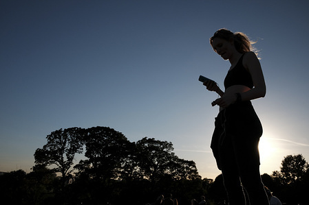 A woman looks at her phone on Primrose Hill as dusk begins to fall over London.