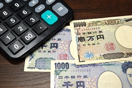 In this photo illustration, a black calculator overlaps with Japanese 1,000 - yen and 10,000 - yen banknotes on a wooden table. business, economy, currency, cash, bill, bills, money, note, notes, 10000 yen, banknotes, japanese, yen, finance, ten thousand, sample, keyboard, laptop