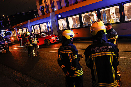 Firefighters are seen working at the scene where a red Mercedes was involved in a collision with a tram near Waldplatz station in the city center of Leipzig in the evening. Tram traffic was temporarily suspended in both directions.