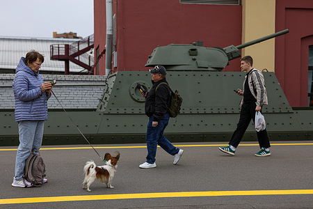 Residents and visitors with a small dog walk past a replica of the BP-43 armored train platform during a military-historical exhibition at the Baltiyskiy Railway Station. A large-scale historical and patriotic exhibition arrived at the Baltic Station in St. Petersburg. The event featured an authentic replica of a BP-43 armored train and a retro train carrying military equipment from the Great Patriotic War. Organized by the Oktyabrskaya Railway and the Russian Railway Museum, the exhibition marks the 81st anniversary of Victory Day on May 9.