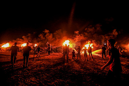 Palestinian protesters burn tires during a night demonstration on the border between Gaza and Israel in solidarity with Palestinian prisoners in Israeli prisons.